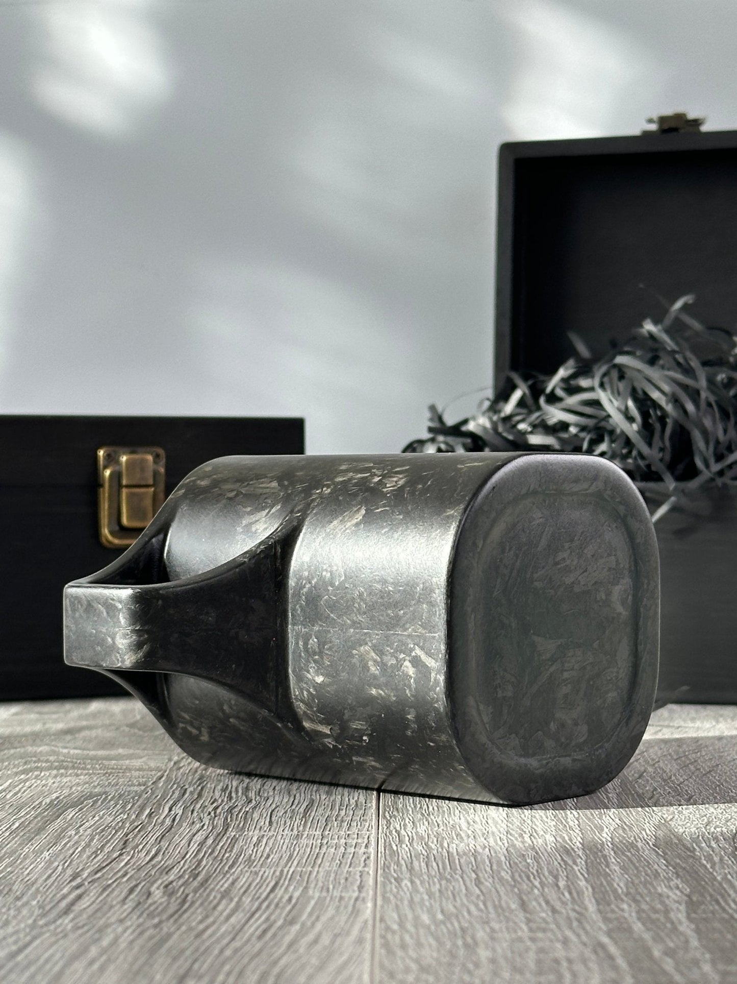 Bottom and under-handle view of carbon fibre mug – Quotidiano Edition 2 – wooden boxes in background