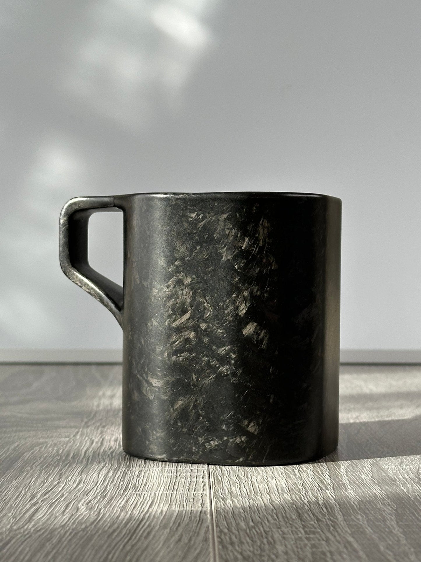 Virgin carbon fibre mug – Quotidiano Edition 2 – side profile with handle turned left, clean backdrop