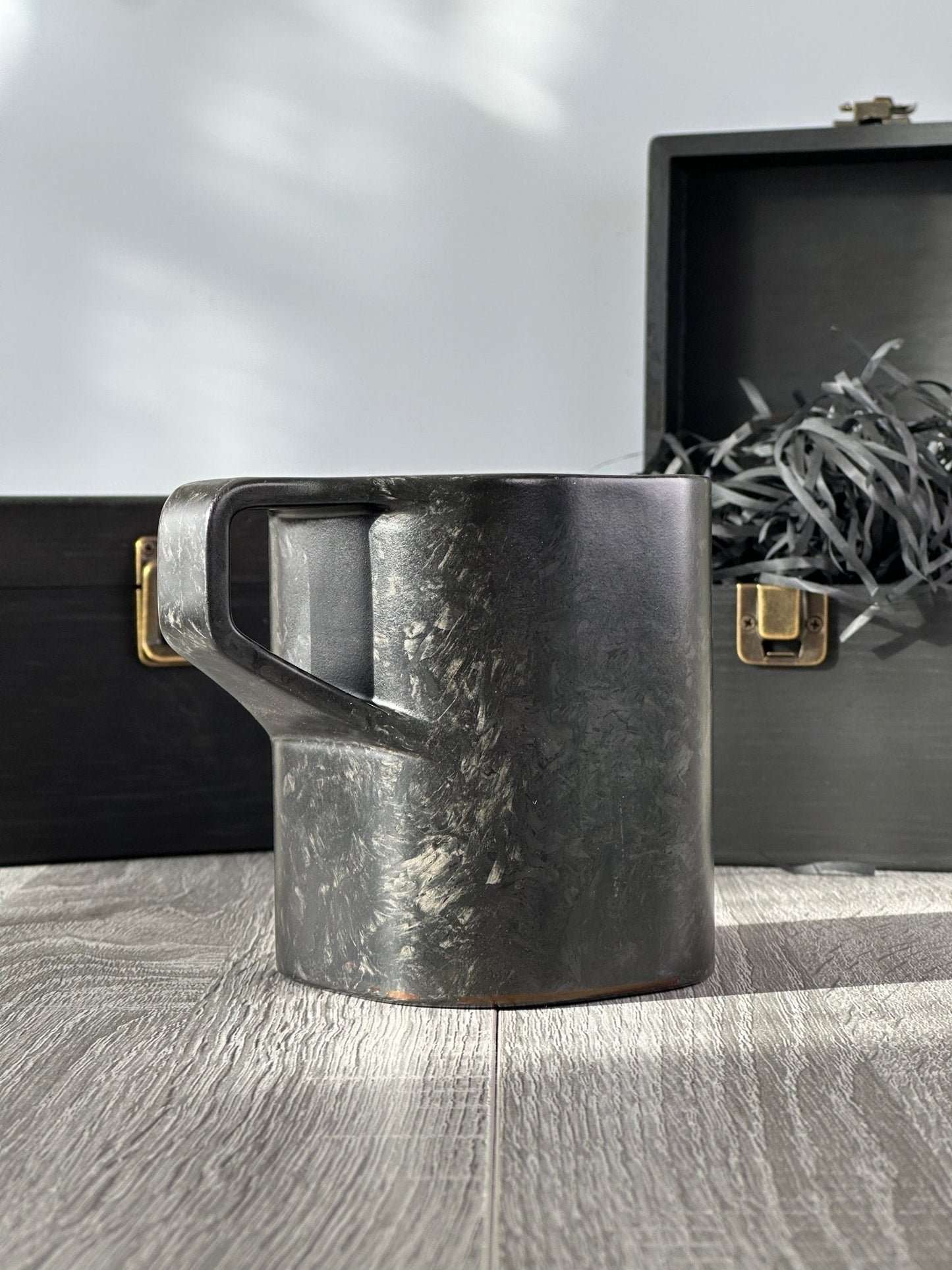 Front-angled view of carbon fiber mug with premium wooden gift packaging