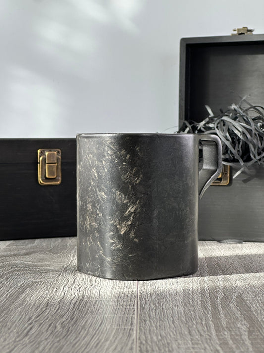 Forged carbon fiber mug with premium wooden boxes in background – angled rear view